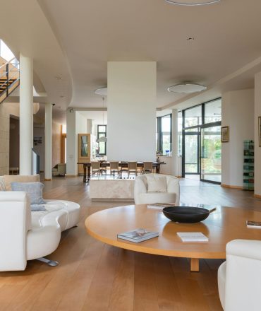 Large apartment with modern interior and soft armchair with white sofa near stairs