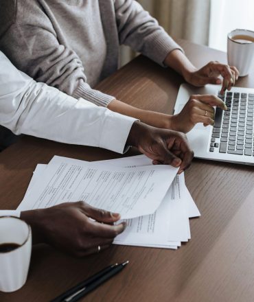 Close-up of diverse colleagues working together on a laptop in a modern office environment.